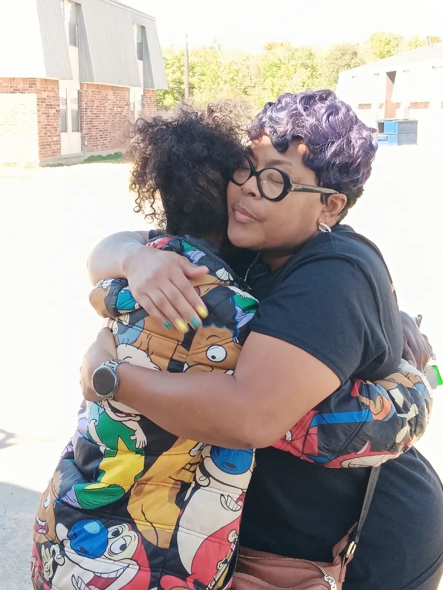Two women share a long embrace at an outreach event
