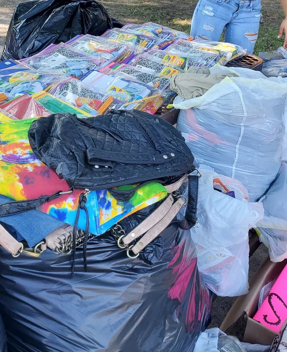 Backpacks and school supplies laid out on a table for families